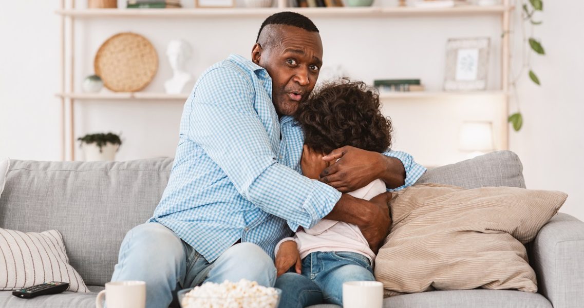 scared kid watching movie with dad